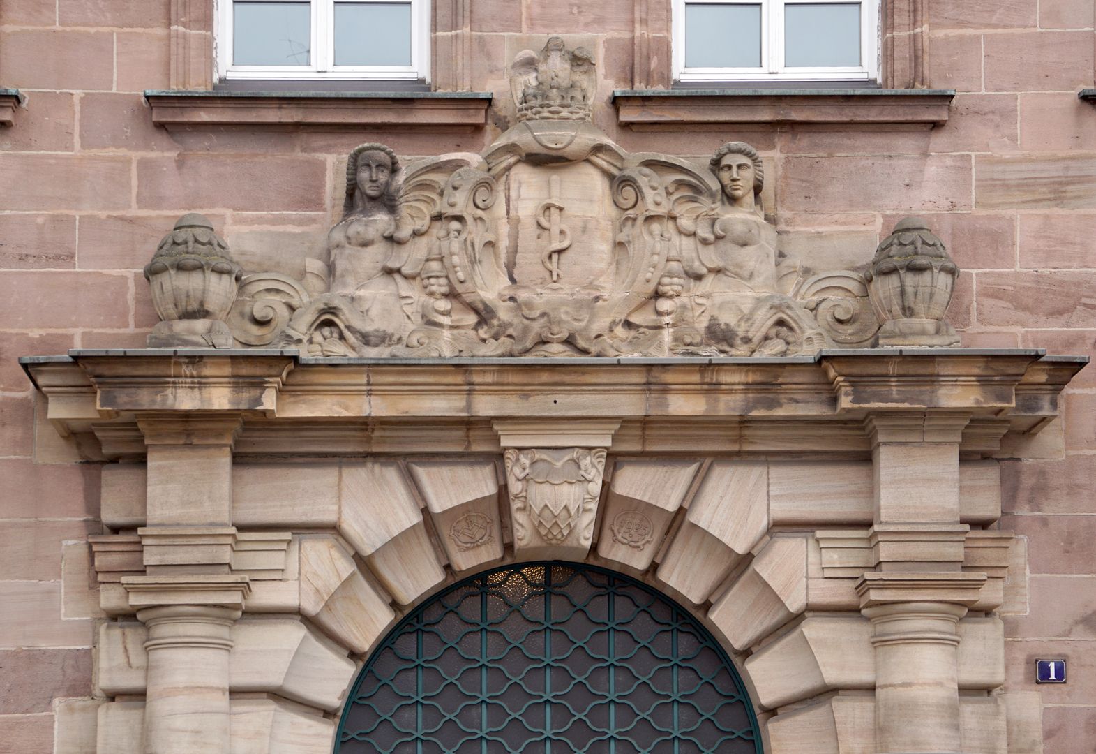 Fassadenschmuck an der ehemaligen AOK / Grillenberger Straße Bekrönung des Haupteinganges, der Äskulapstab als Sinnbild der Medizin wird von zwei Sphingen gerahmt