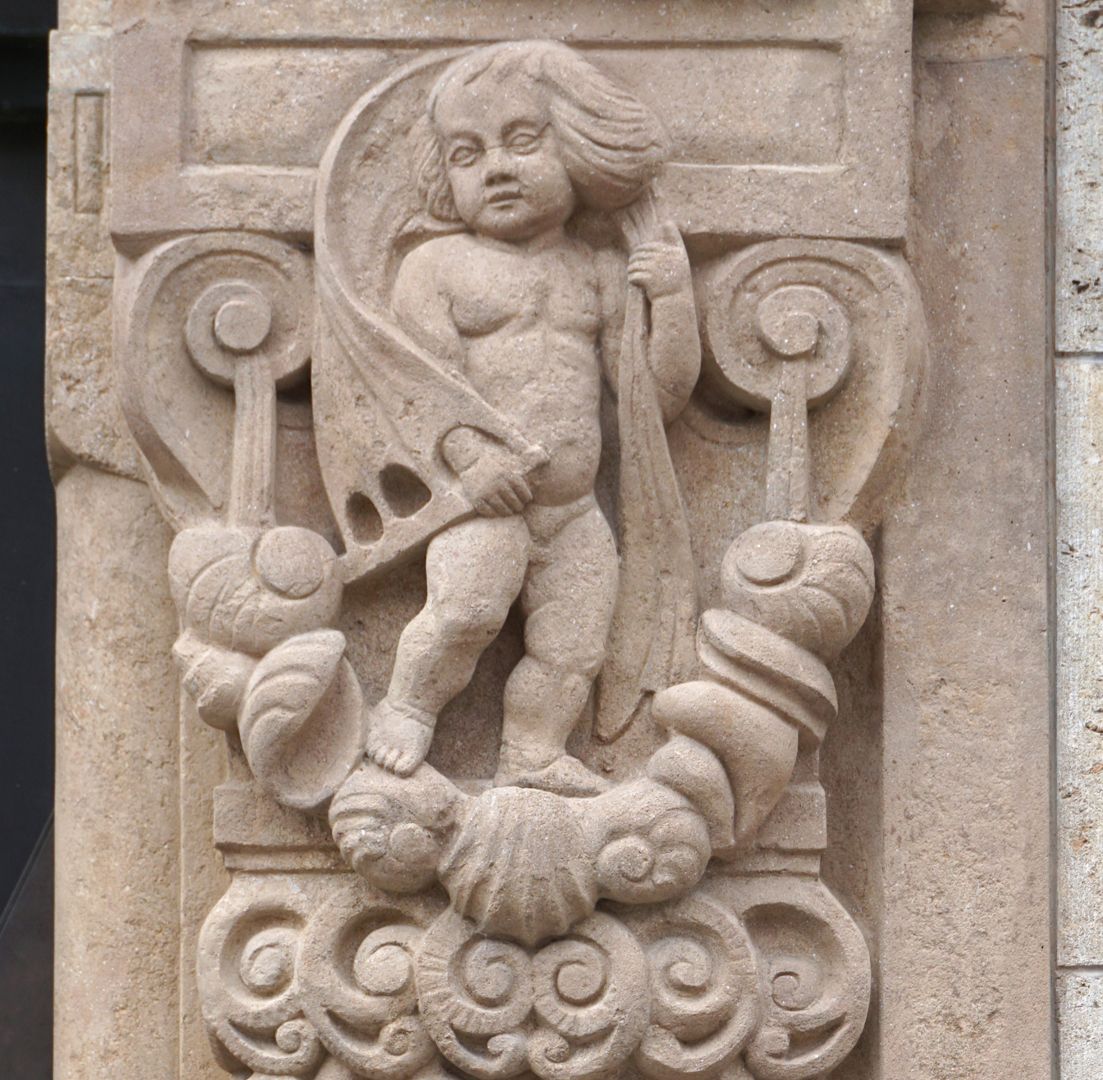 Portal right portal reveal, detail with putto standing on a shell pendant and a canvas inflated by the wind over his shoulders