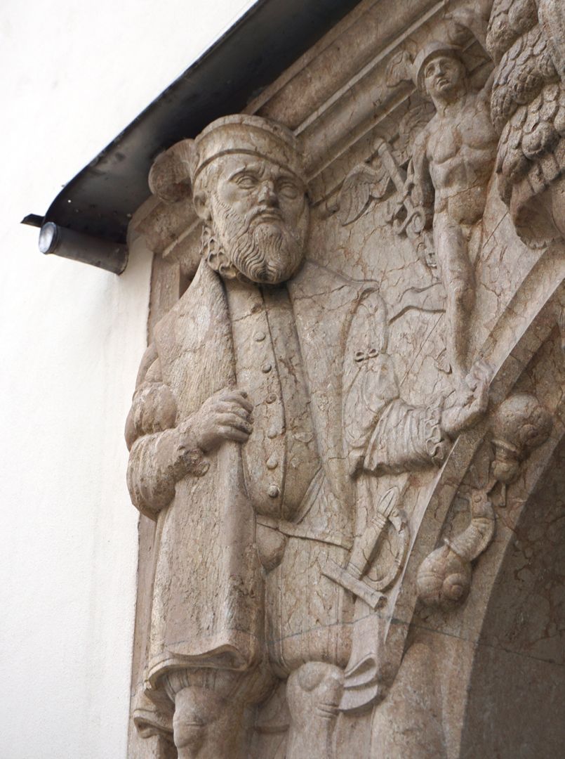 Portal Upper left corner: a citizen in Renaissance dress carries Mercury (Roman patron god of merchants) in his left hand, oblique view