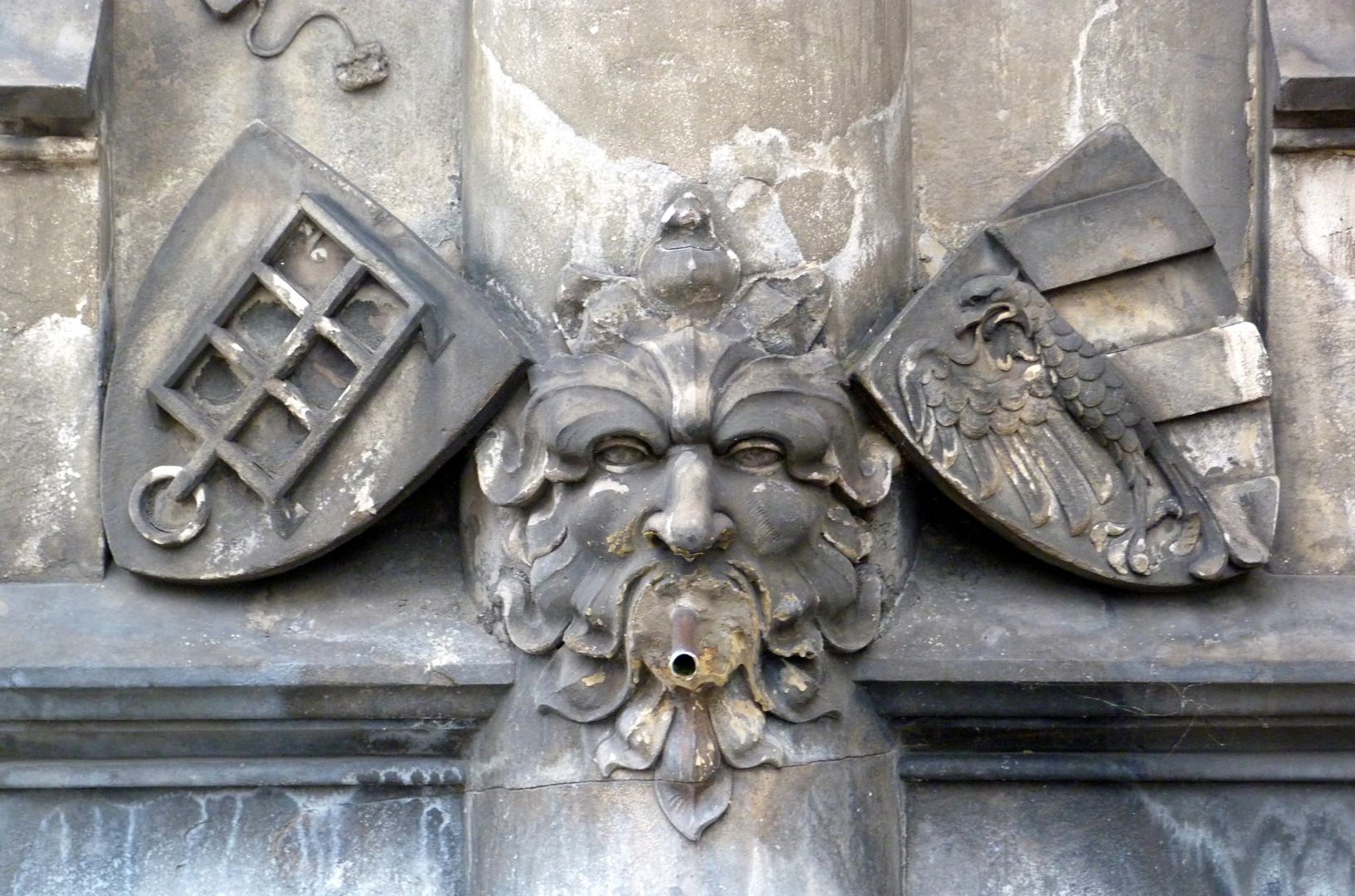 Devil's Fountain Gargoyle with leaf mask in the centre, on the left with the coat of arms of St. Lawrence (depicting the grate on which he was martyred) and on the right the Nuremberg city coat of arms.